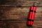 Red explosive dynamite bomb on wooden background, top view. Space for text