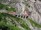 Red express train on scenic stony St. Gotthard railway bridge and tunnel, swiss Alps, SWITZERLAND