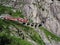 Red express train on scenic stony St. Gotthard railway bridge and tunnel, swiss Alps, SWITZERLAND