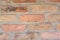 Red faded old bricks background with flaws and splits