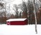 A red farm shed in winter after a light snowfall