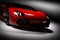 Red fast sports car in spotlight, black background. Shiny, new, luxurious.