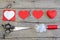 Red felt heart, cut felt parts in shape of a heart, paper pattern, scissors, thread, needle on a wooden table. Felt heart craft