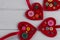 Red felt hearts crafts decorated with beads and buttons on white background.