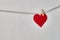 Red felt valentine heart hanging from a rope on white wooden background. Copy space
