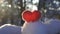Red felted woolen heart on the snow and backlighted by the winter setting sun slow motion
