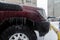 The red fender, wheel and bumper of the SUV are very icy due to the rain in winter. Icicles hang down.