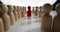 Red figurine stands between long rows of wooden figures