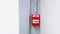 Red fire alarm button for pull out in emergency case happen installed on gray or grey steel pole with white wall background