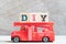 Red fire truck hold block in word DIY abbreviation of do it yourself on wood background