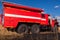 Red firetruck car Ural rides through the autumn field with yellow and faded grass against the blue sky and clouds. The concept