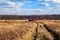 Red firetruck car Ural rides through the autumn field with yellow and faded grass against the blue sky and clouds. The concept