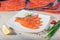 Red fish sliced in slices lies on a white plate. Around vegetables and slivers