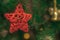 A red five-pointed star hangs on a Christmas tree