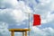 Red flag next to a lifeguard chair at the beach. Swimming in the sea is not allowed.