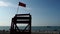Red flag on a wooden rescue tower. Symbol of danger. A flag prohibiting swimming on the beach.