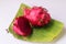 Red flesh dragon fruit, Pitaya or Pitahaya, cut into slices ready to eat, placed on a banana leaf and with a white background.