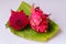 Red flesh dragon fruit, Pitaya or Pitahaya, cut into slices ready to eat, placed on a banana leaf and with a white background.