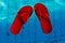 Red flip-flops floating in a swimming pool, a top view