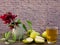 Red flower with green leaves  in  small vase  , green apples and apple juice on wooden table