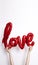 Red foil Love balloon held against a plain white background