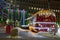 The red food truck decorated with garlands and lights stands on the square against the background of a Christmas tree