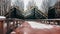 The red footpath in the park is fenced with metal railings and covered with snow.