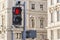 Red forbidding traffic light prohibit for pedestrians to cross the street in european city on background of old classic building.