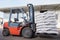 Red forklift lifts pallet with white bags