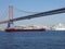 A red freighter and a liner under the bridge of April 25 in Lisbon, Portugal, Europe