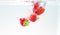 Red fresh fruit strawberries falling into water with splash on white background, strawberry for health and diet, nutrition