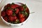 Red fresh strawberry in a bowl on white background with copy space