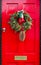 Red front door to UK house with Christmas wreath