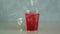Red fruit ice tea. Glass of Ovshala lemonade. Ice cube fall in take away plastic cup with drink.
