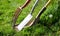 A red gardening fork and two gardening spades in grass