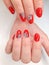Red gel polish with a black geometry design on a white background. Women`s hands with red nail polish.