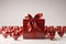 Red gift box with bow surrounded by many hearts on white background in a strict and simple style.