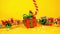 A red gift box with a Christmas present comes down from above on a candy cane on a yellow background with Christmas decorations.