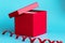 Red gift box with lid ajar and spiral ribbon on blue background. Closeup. Holidays concept. Mockup for greeting