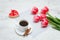 Red gingerbread, pink tulips and mug of coffee. Light wooden bac