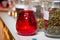 A red glass with a candle and jars of dry tea on the counter in a restaurant, in a private kitchen, in the special shop, in spa