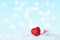 Red glittering heart with gift box on snow. Defocused lights on soft blue background