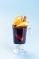 Red glogg or mulled wine with orange slices and cinnamon stick on blue background, vertical