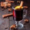 Red glogg or mulled wine with orange slices and cinnamon stick on dark wooden background, square format