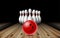 Red glossy ball rolling on bowling alley line to ten placed in order white bowling pins.