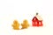 Red glossy Christmas decoration - little house and two gingerbread figures standing on white fur background