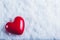 Red glossy heart on a frosty white snow background. Love and St. Valentine concept.