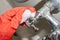 A red-gloved hand rubs a water knob on a chrome-plated faucet covered with limestone with a white melamine sponge