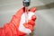 Red gloved hand wets white melamine sponge under tap water in bathroom