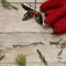 Red gloves and holly on a wooden surface